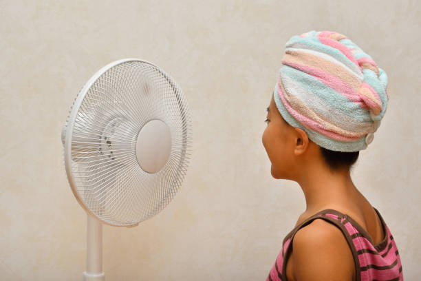 Japanese girl cools down after a bath by electric fan - rear view