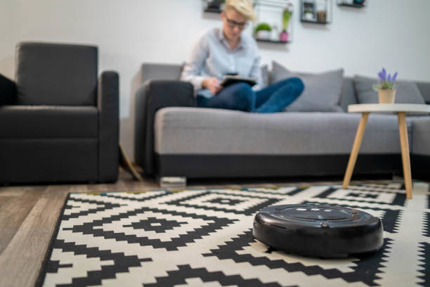Robotic vacuum cleaner cleaning the room while woman resting on sofa, closeup