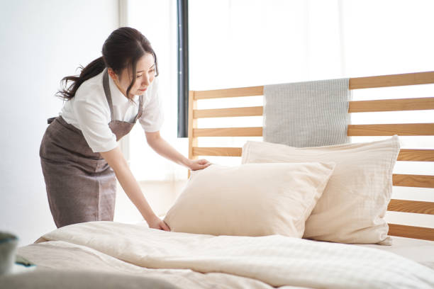Asian woman making a bed in the bedroom